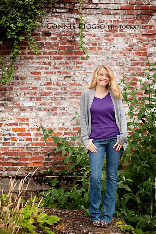 Standing by brick purple shirt Tacoma Best Senior Photographer